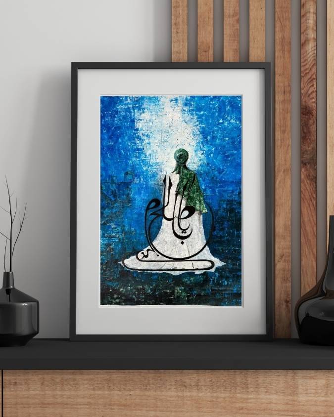 Al-Faraj painting in a black frame leaning on a dark sideboard, a seated green-robed figure against deep blue