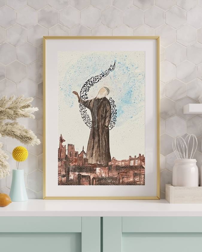 Framed Sufi artwork on a shelf with dried grasses, robed figure and pale blue calligraphy above a brown skyline